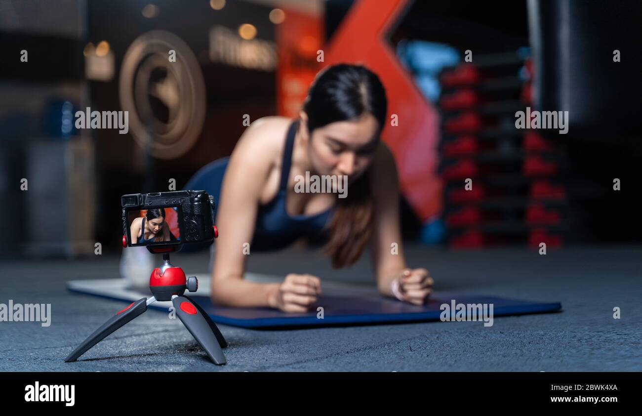 Die Kamera auf dem Stativ macht Bilder oder Videos. Asiatische Frauen Trainer in guter Form Lehre oder Durchführung einer Probe von Plank Posen ist ein Körpergewicht Stockfoto