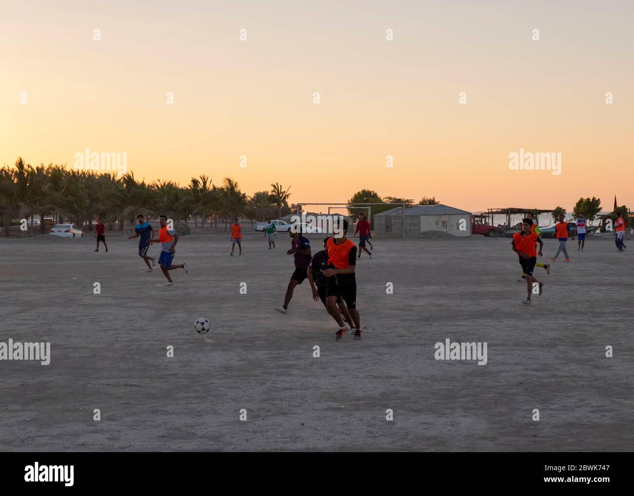 Junge Männer, die Fußball spielen in Al Ghubra Vorort bei Sonnenuntergang, Maskat, Oman Stockfoto