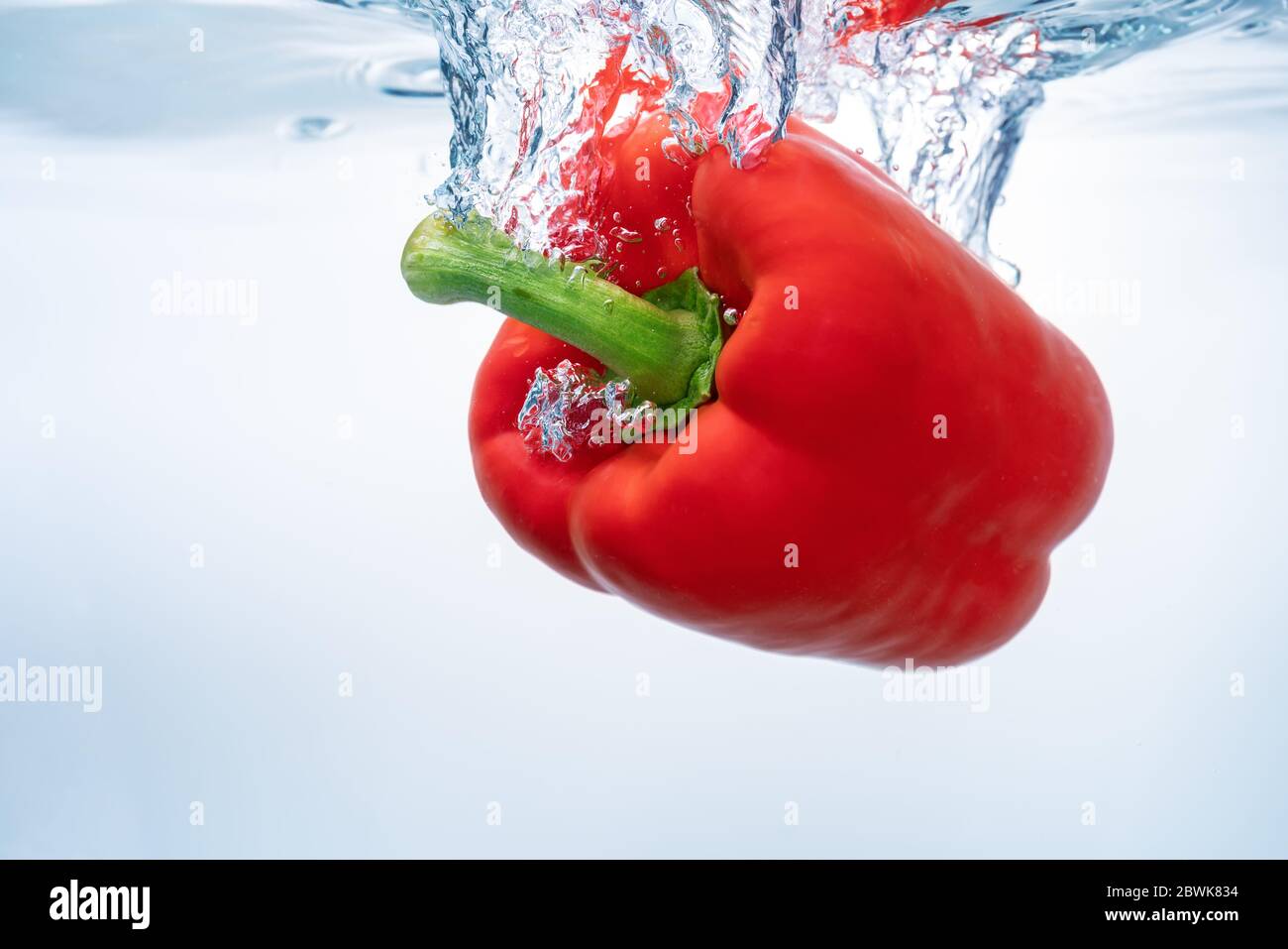Rote Paprika auf der Oberfläche von ökologischem klarem Wasser. Nahaufnahme. Stockfoto