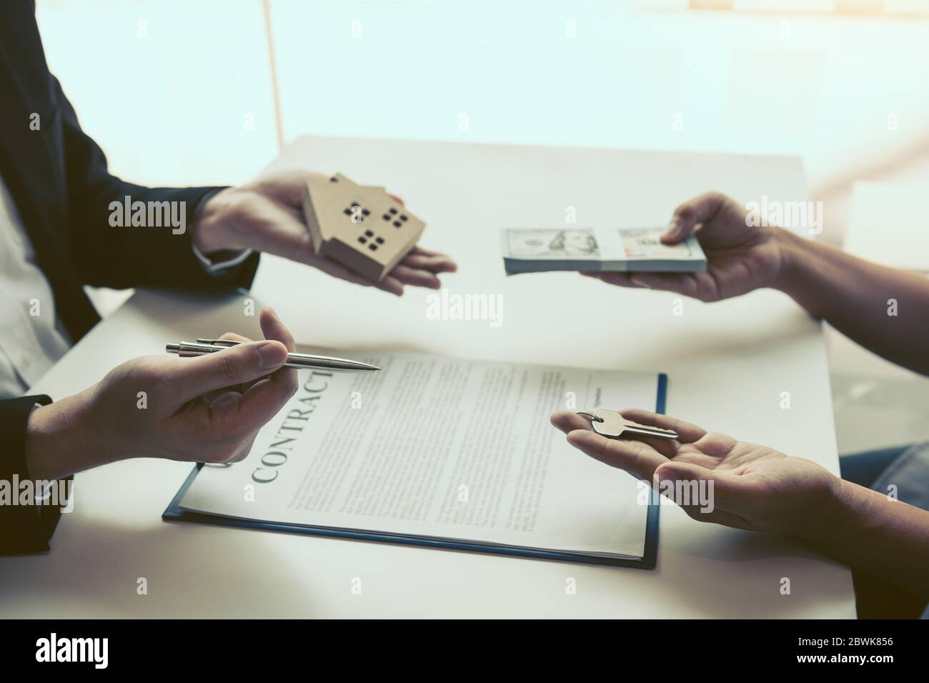 Neue Hauskäufer unterzeichnen einen Hauskaufvertrag am Schreibtisch des Agenten. Stockfoto