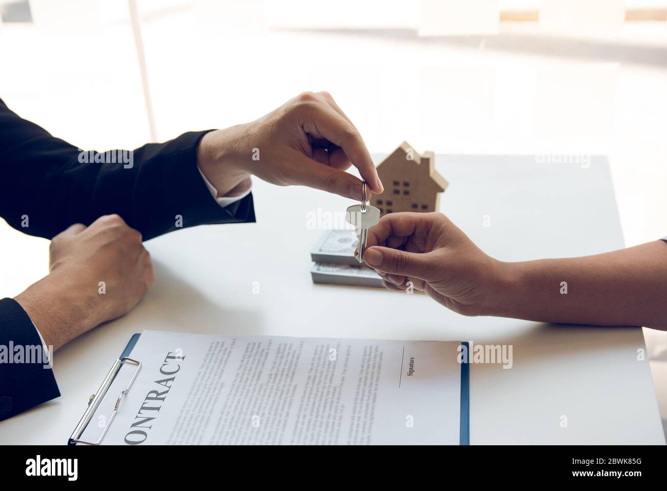 Neue Hauskäufer unterzeichnen einen Hauskaufvertrag am Schreibtisch des Agenten. Stockfoto