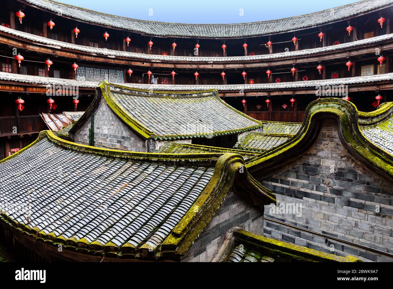 Blick auf die inneren Strukturen eines Fujian Tulou: Mehrere kleine Häuser aus Ziegelsteinen mit moosbedeckten Dächern. Stockfoto