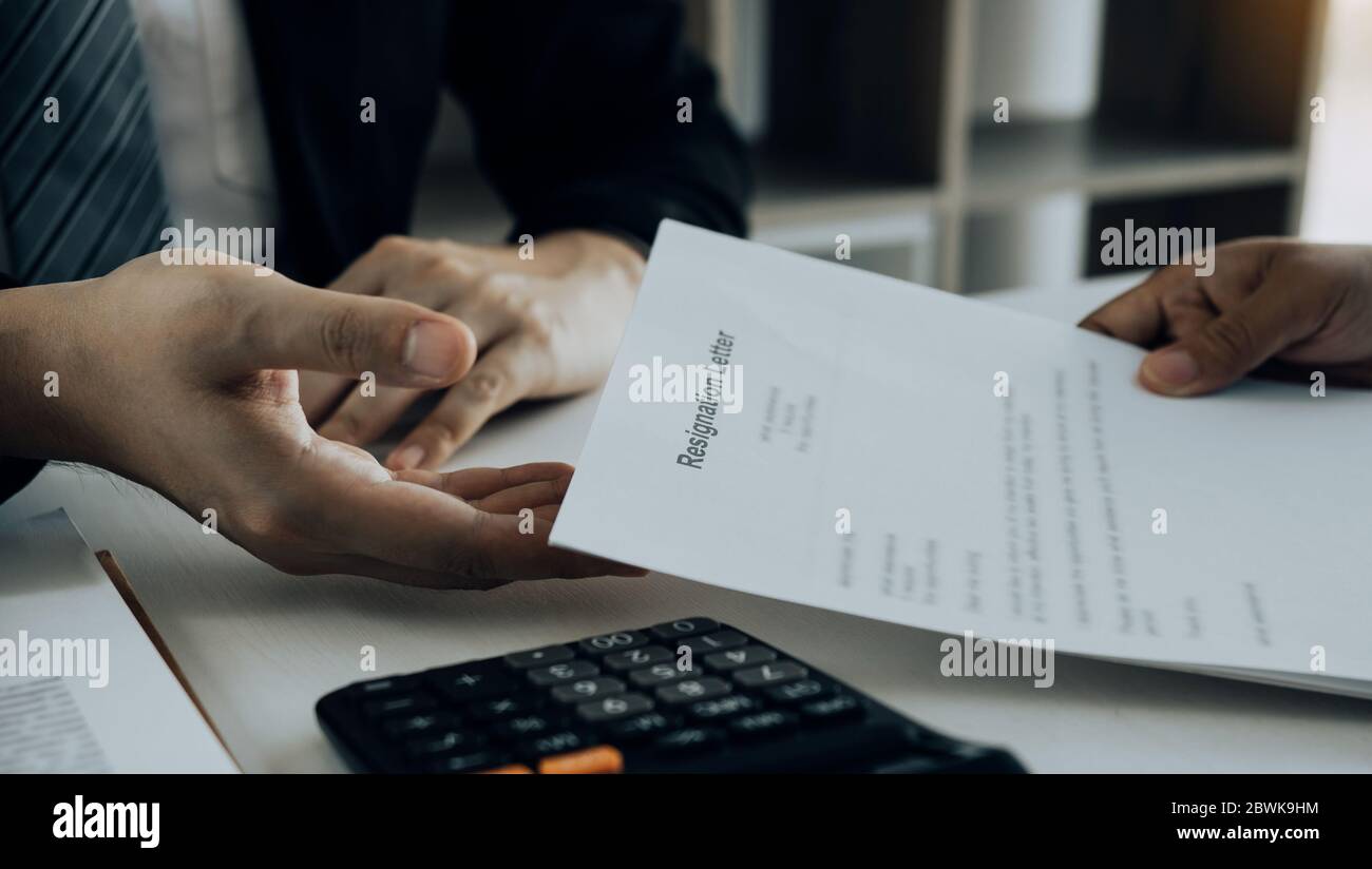 Die Mitarbeiterin nimmt den Griff zum Rücktrittsumschlag und wird der Managerin übergeben. Stockfoto