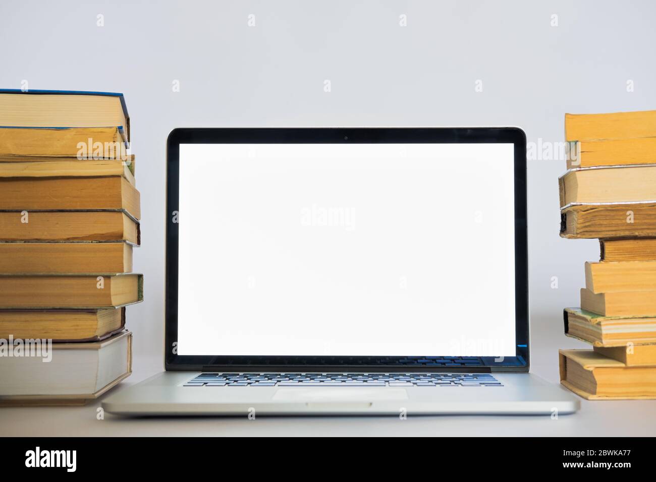 Laptop-Computer mit weißem Bildschirm auf dem Stapel alter Bücher. Alte versus neue Technologie und Bildung bedeutet Stockfoto