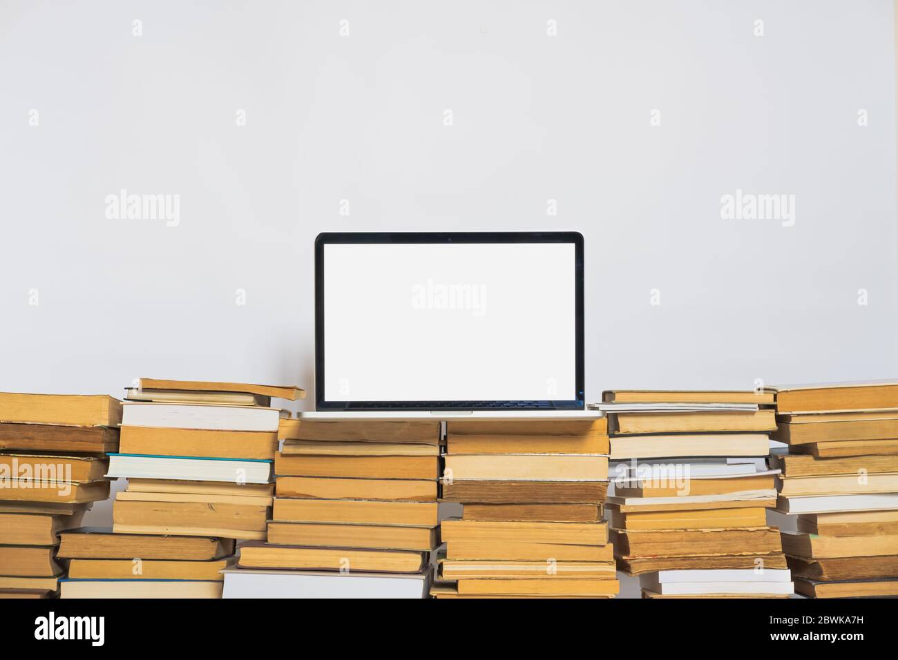 Laptop-Computer mit weißem Bildschirm auf dem Stapel alter Bücher. Alte versus neue Technologie und Bildung bedeutet Stockfoto