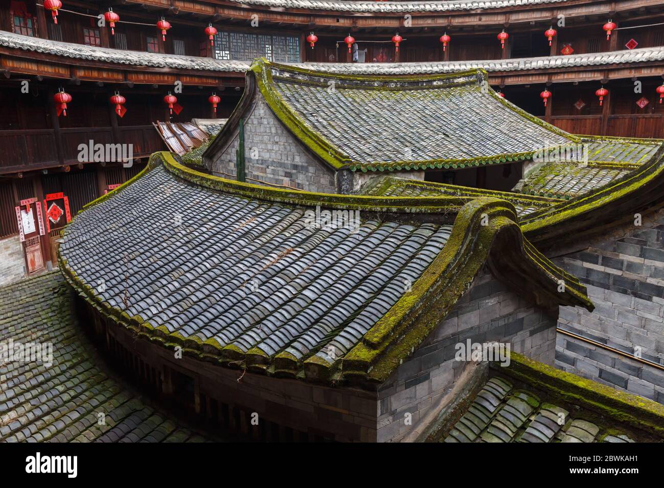 Blick in den Innenhof eines Fujian Tulou: Kleine Backsteingebäude mit moosbedeckten Dachziegeln. Stockfoto