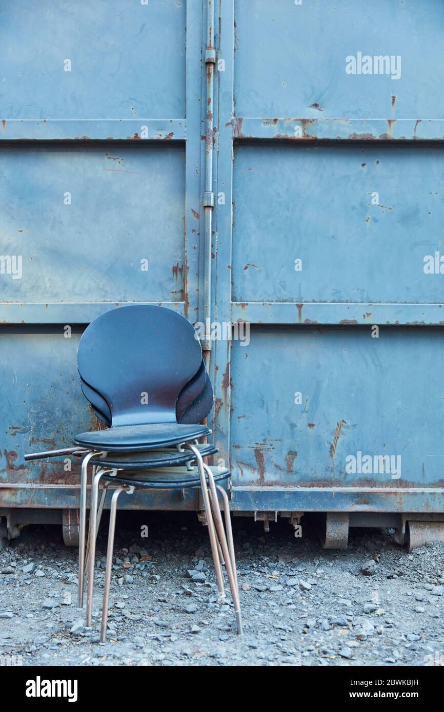 Alte Stühle als sperrige Müllhaufen vor einem alten Container Stockfoto