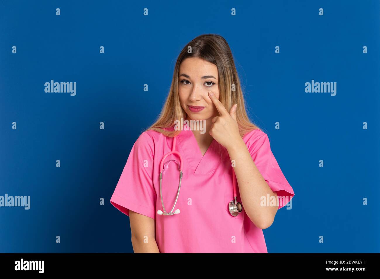 Blonde Arzt mit rosa Uniform auf blauem Hintergrund Stockfoto