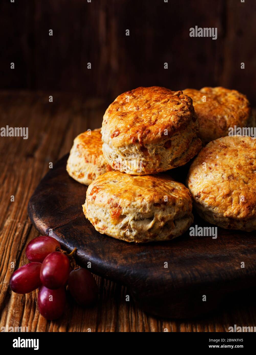 Port und Stilton Scones serviert auf runden Holztäfelchen mit roten Trauben Stockfoto