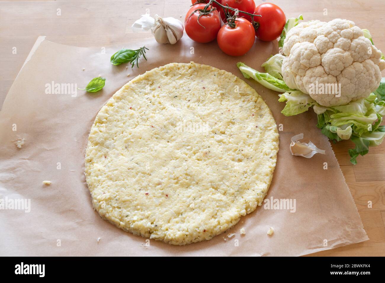 Rohe Pizza Basis aus geschreddertem Blumenkohl auf Backpapier, gesunde pflanzliche Alternative für Low Carb und ketogene Ernährung, Kopierraum, ausgewählten Fokus, n Stockfoto