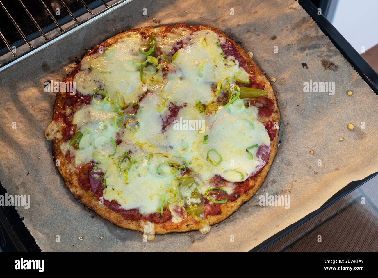 Gebackene Pizza aus Blumenkohlenkruste mit Salami und Käse frisch aus dem Ofen, ausgewählte Fokus, schmale Schärfentiefe Stockfoto