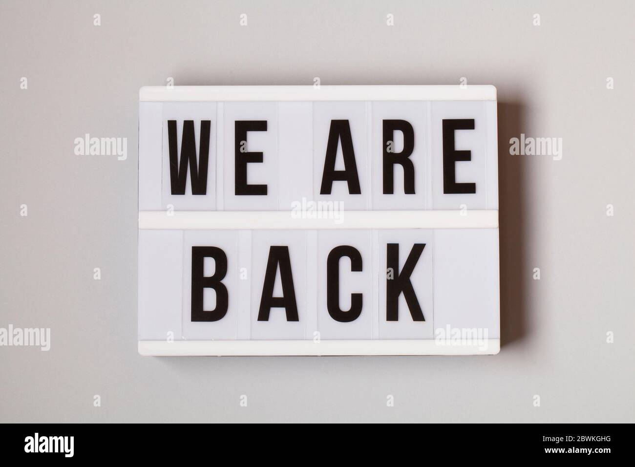 Leuchtkasten mit Text SIND WIR WIEDER auf weißem Hintergrund , Wiedereröffnung nach covid-19 Shutdown-Konzept Stockfoto