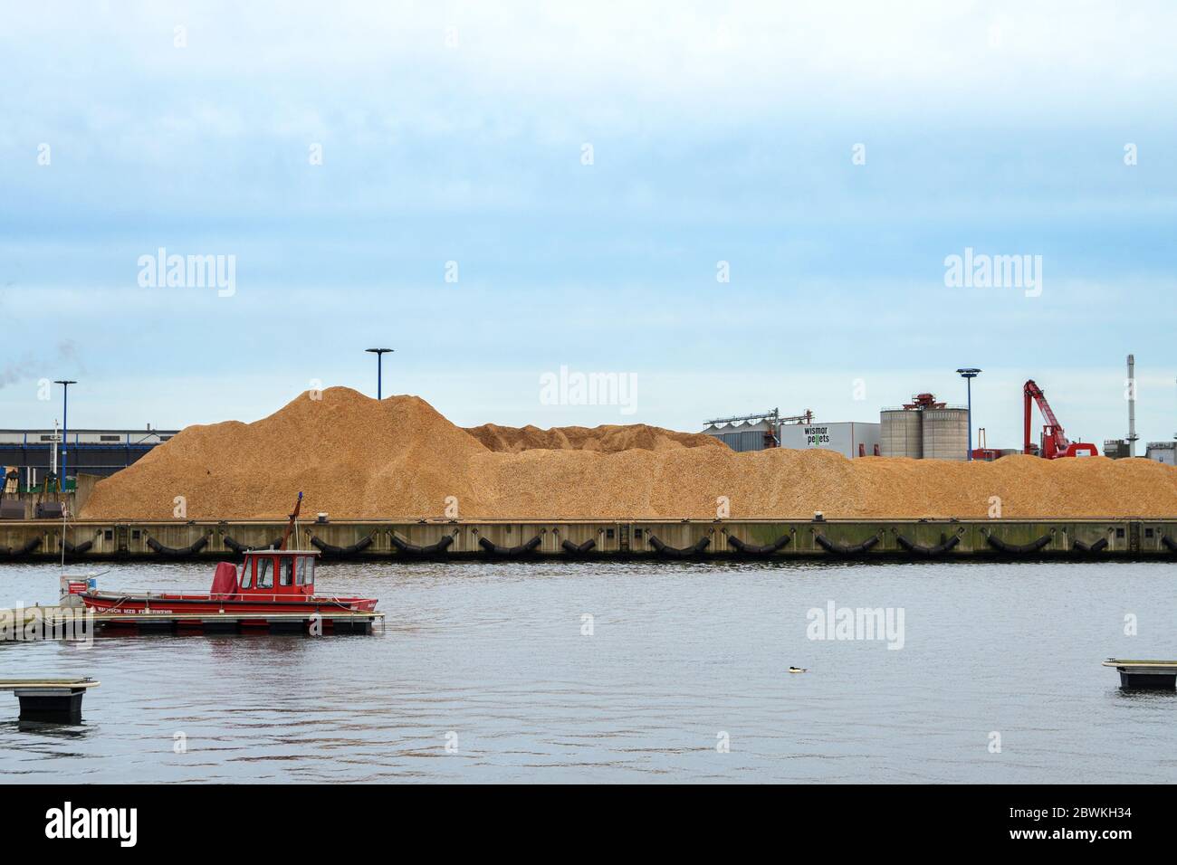 WISMAR, 2. FEBRUAR 2020: Holzhackhaufen, ein Feuerboot und eine Holzverarbeitungsfabrik im Holzhafen Wismar in Mecklenburg-Westpommern Stockfoto