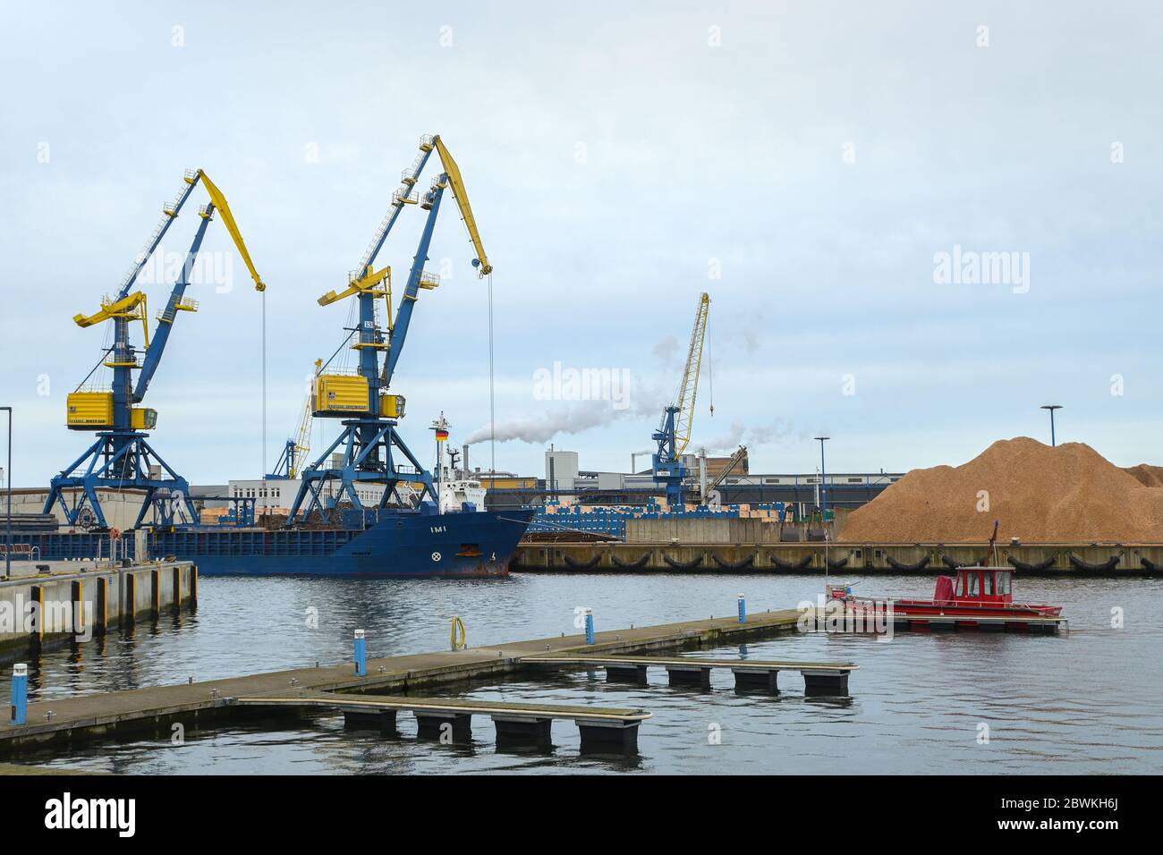 WISMAR, 2. FEBRUAR 2020: Kranboot, Feuerwehrschiff und Holzverarbeitungsfabrik im Holzhafen Wismar in Mecklenburg-Westpommern Stockfoto