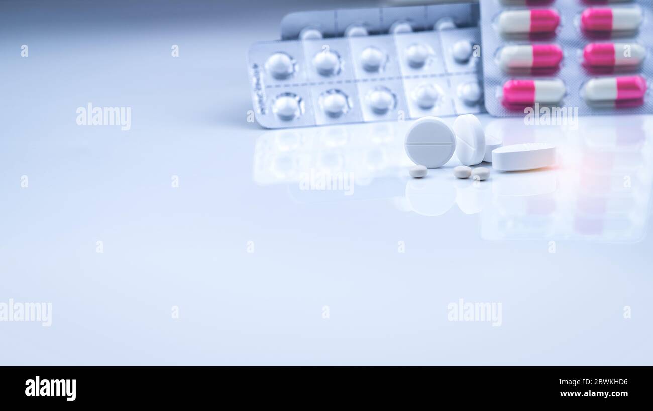 Weiße Tabletten Pillen auf verschwommenen weiß-rosa Kapseln und runde Tabletten in Blisterverpackung. Apotheke Drogerieprodukte. Pharmaindustrie. Gesundheitswesen Stockfoto