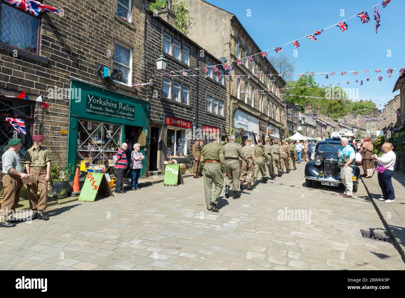 Re-Darsteller, die als Soldaten der Heimatwache gekleidet sind, die während des 1940-Sekunden-Wochenendes des Dorfes in einer Säule die Main Street, Haworth, West Yorkshire, hochmarschieren Stockfoto