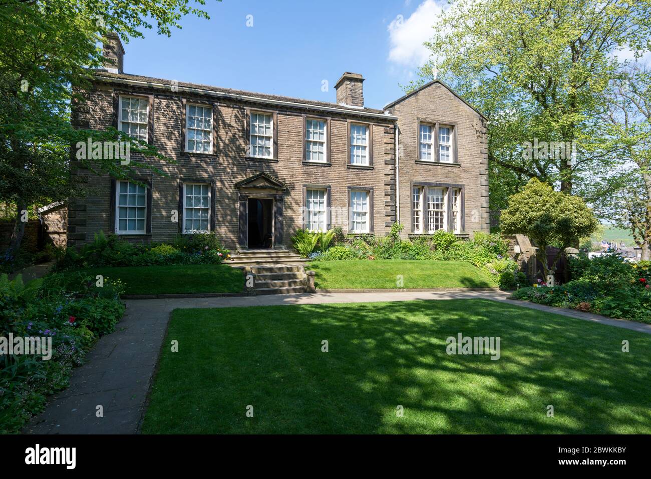 Blick auf das Bronte Parsonage Museum in Howarth, West Yorkshire vom Garten aus an einem sonnigen Sommernachmittag Stockfoto