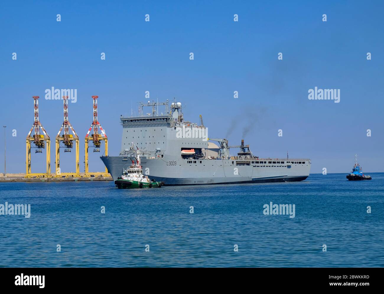 RFA Cardigan Bay wird mit dem Schlepper in Port Sultan Qaboos, Maskat, Oman, gezogen Stockfoto