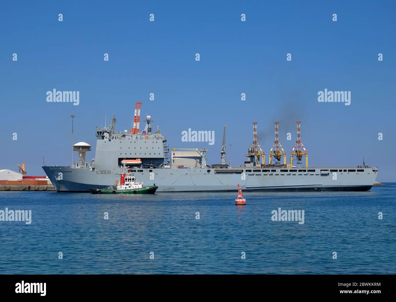 RFA Cardigan Bay wird mit dem Schlepper in Port Sultan Qaboos, Maskat, Oman, gezogen Stockfoto