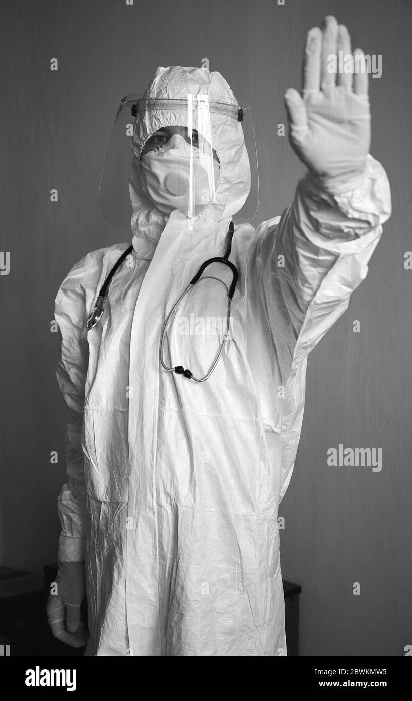 Vertikales Porträt des Arztes in PSA-Anzug, Atemschutzmaske, Handschuhe,  Phonendoskop, zeigt Stoppschild, Besuch des Patienten zu Hause während der  Covid-19 Quarantäne. Schwarzweiß-Bild Stockfotografie - Alamy