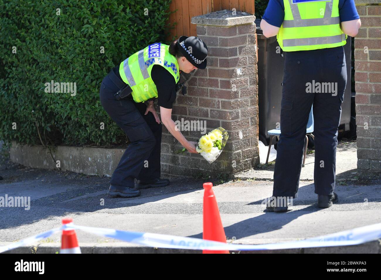 Ein Polizist legt Blumen am Eingang zu einem Haus in der Wessex Road in Salisbury, Wiltshire, auf, wo zwei Frauen am Montag nach einer Störung starben. Ein Mann in den 30er Jahren wurde wegen Mordes verhaftet und in der Melksham Polizeistation in Gewahrsam genommen. Stockfoto