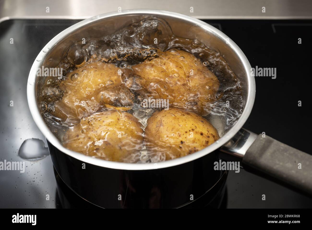 Kochen von Kartoffeln in kochendem Wasser in einem Edelstahltopf auf dem Herd, ausgewählter Fokus, geringe Schärfentiefe Stockfoto