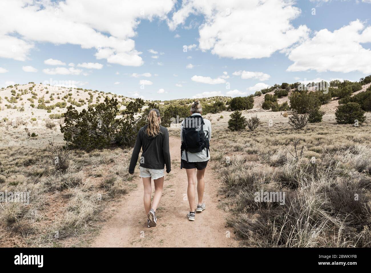 Rückansicht der erwachsenen Frau und ihrer Tochter im Teenageralter, die im Galisteo Basin, NM, wandern. Stockfoto