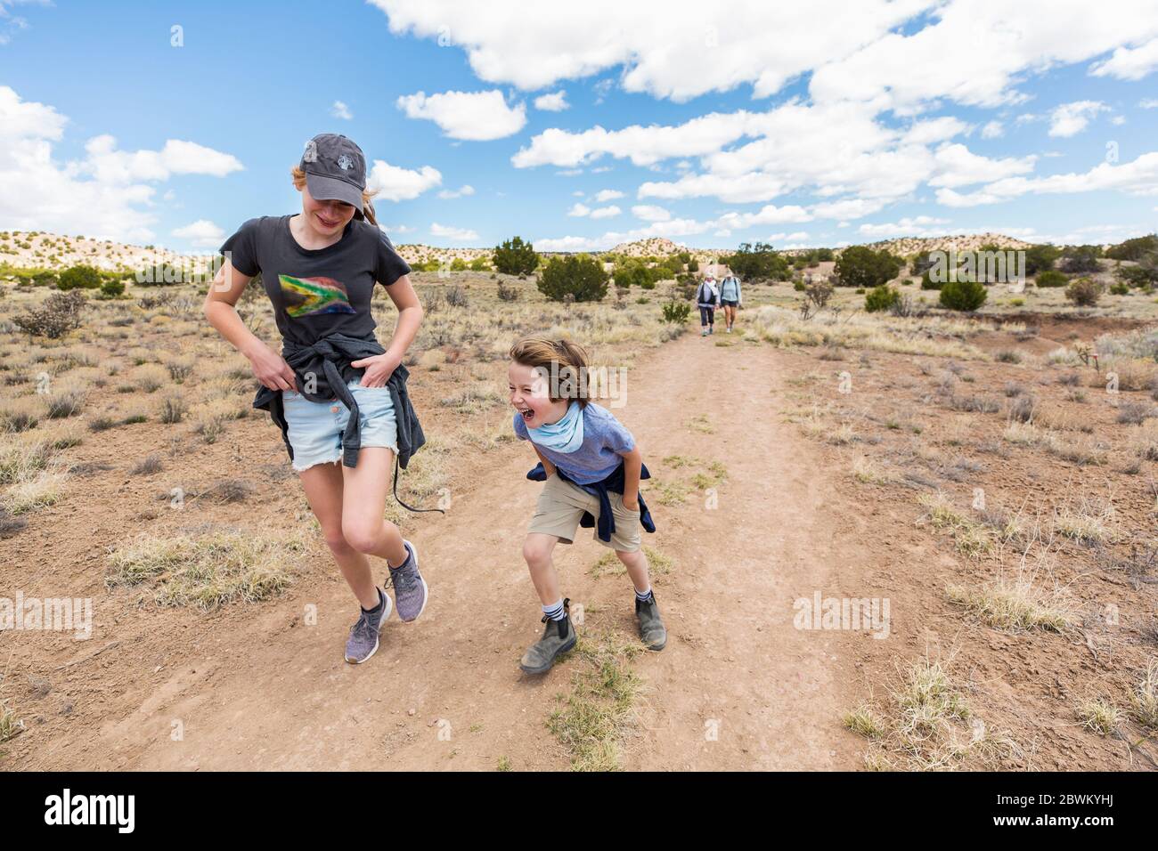 6 Jahre alter Junge läuft auf Wanderwegen mit älterer Schwester, Galisteo Basin, NM. Stockfoto