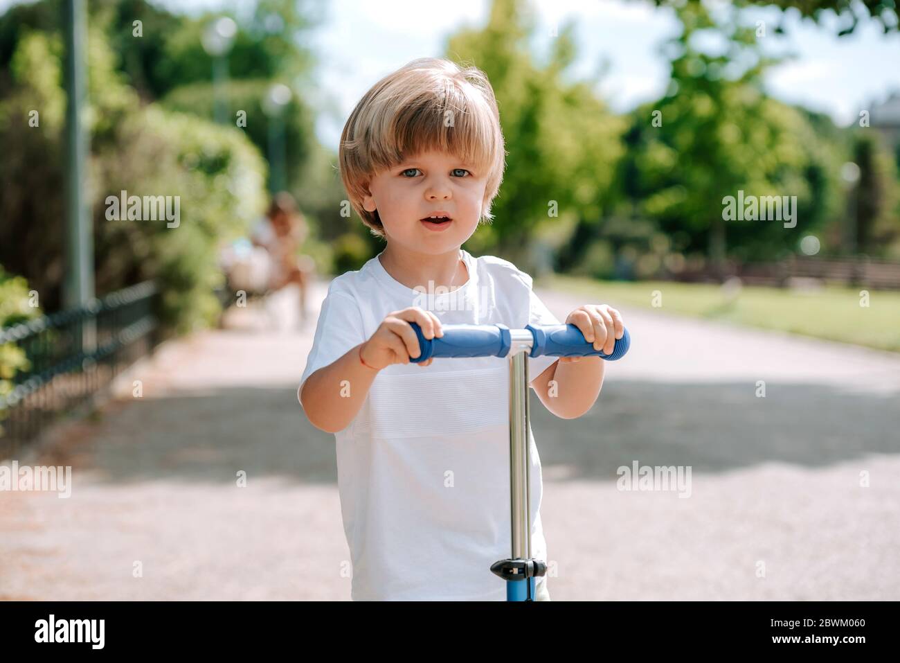 Kind Auf Roller Vorne Mitnehmen Strafe Junge lernen, Roller in einem Park an sonnigen Sommertag fahren