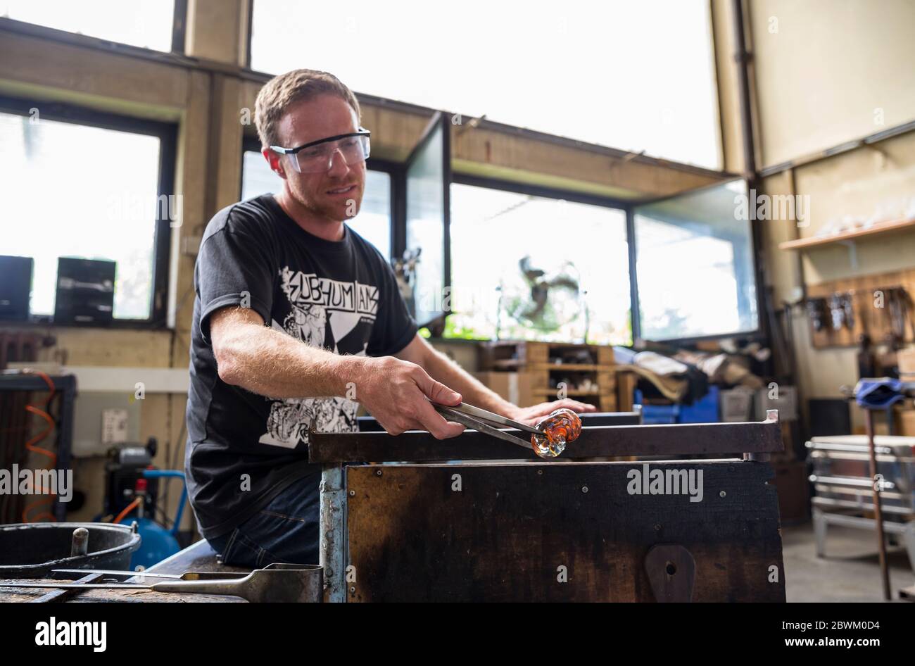 Ein Schüler, der Glas auf einer Werkbank formt während einer Glasbläserstunde in der Berliner Glas-Werkstatt in Wedding, Berlin Stockfoto