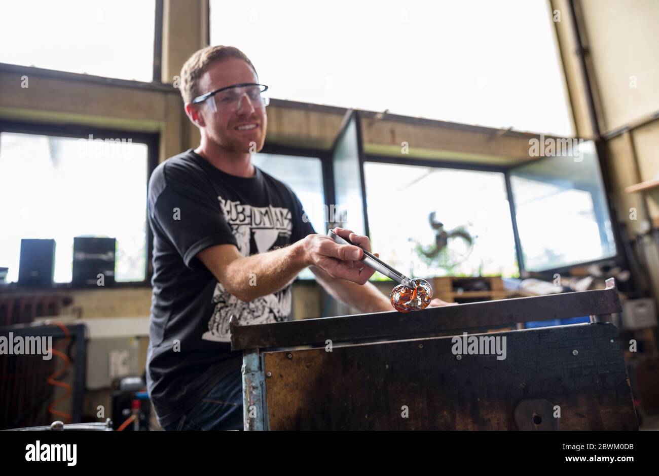 Ein Schüler, der Glas auf einer Werkbank formt während einer Glasbläserstunde in der Berliner Glas-Werkstatt in Wedding, Berlin Stockfoto