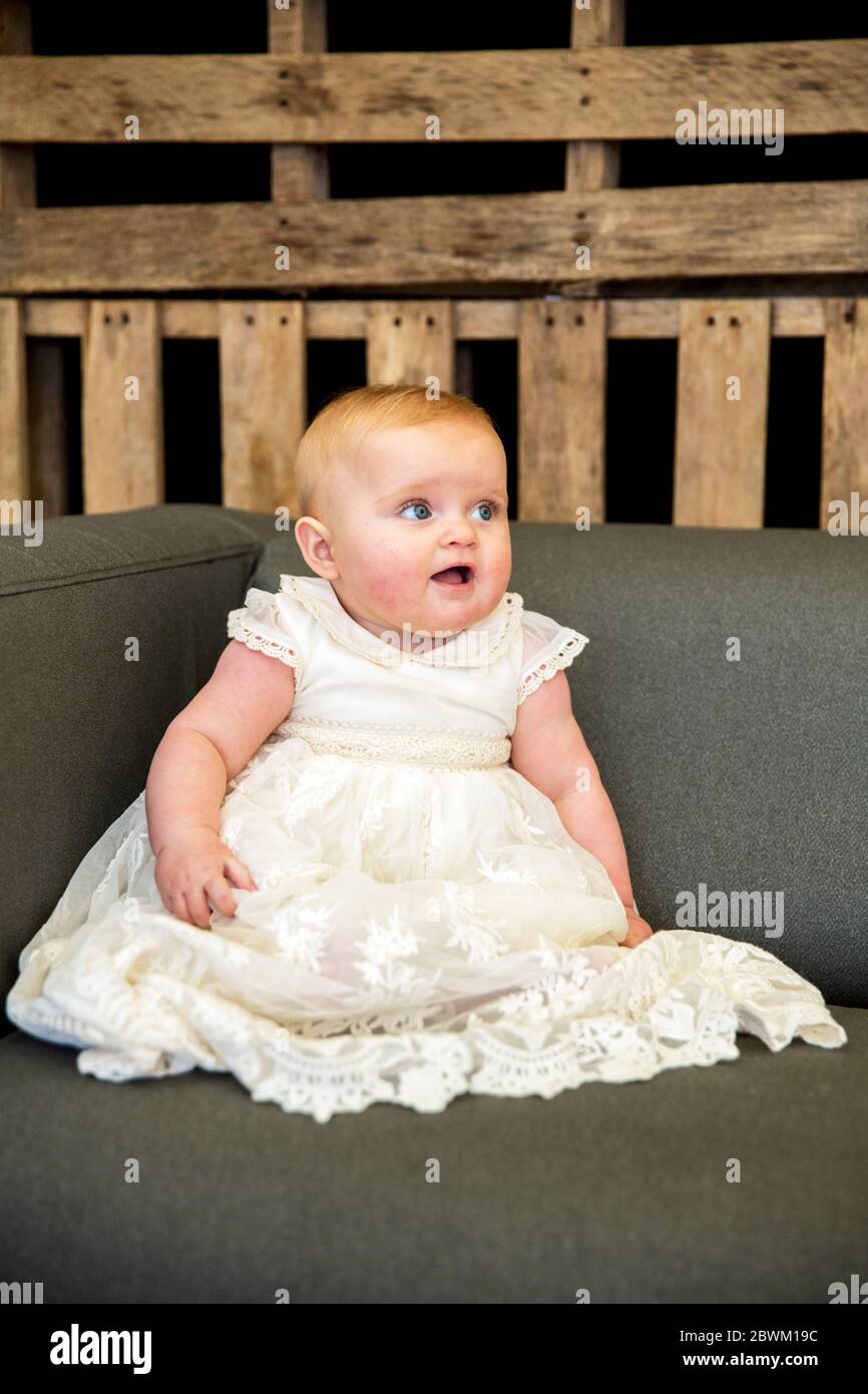 Portrait des kleinen Mädchens in weißem Kleid während der Namensgebung in einer historischen Scheune. Stockfoto