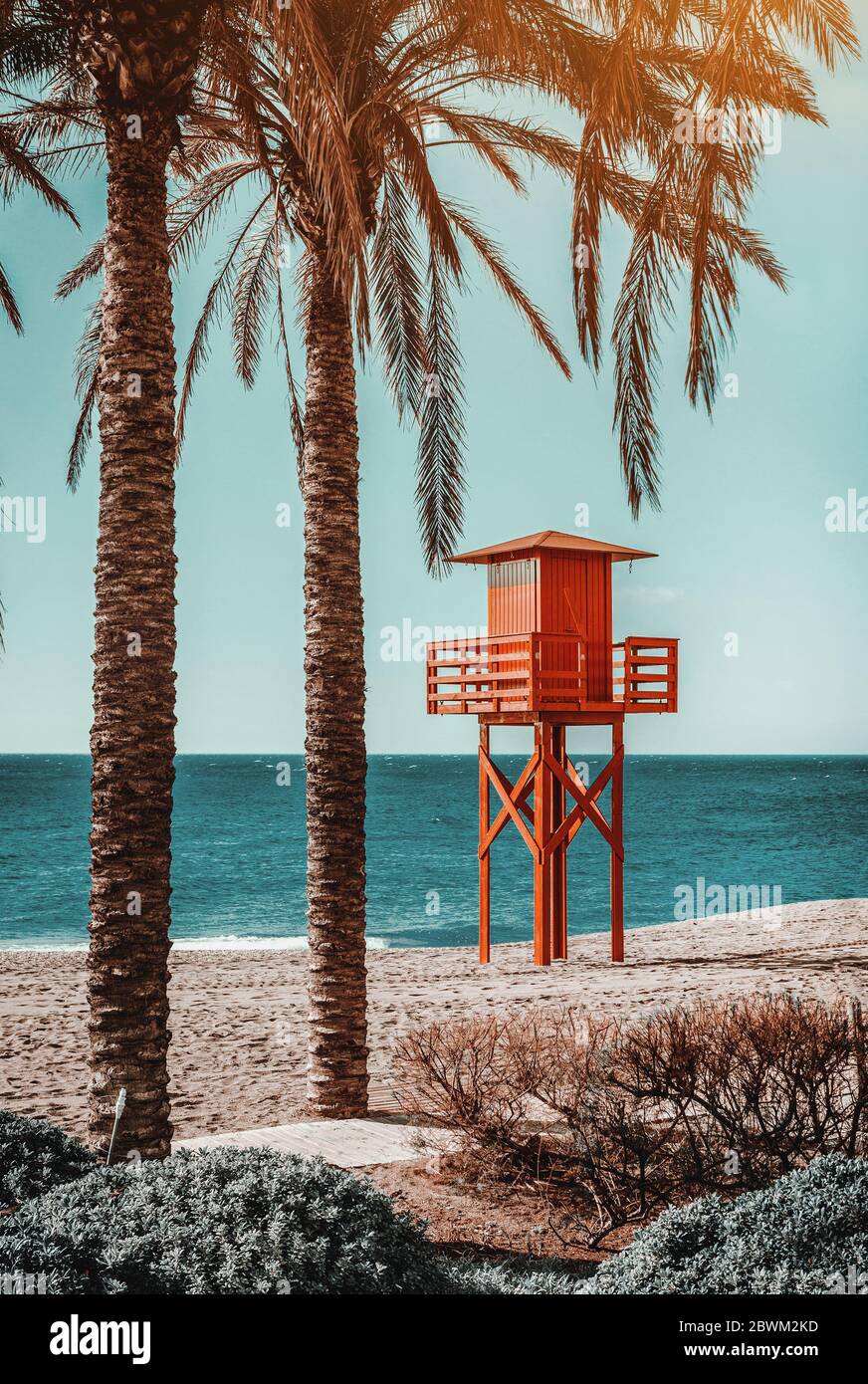 Roter hölzerner Rettungsschwimmer Turm, Palmen am leeren Strand des spanischen touristischen Strandes der Stadt Benalmádena, ruhiges blaues Mittelmeer. Spanien Stockfoto