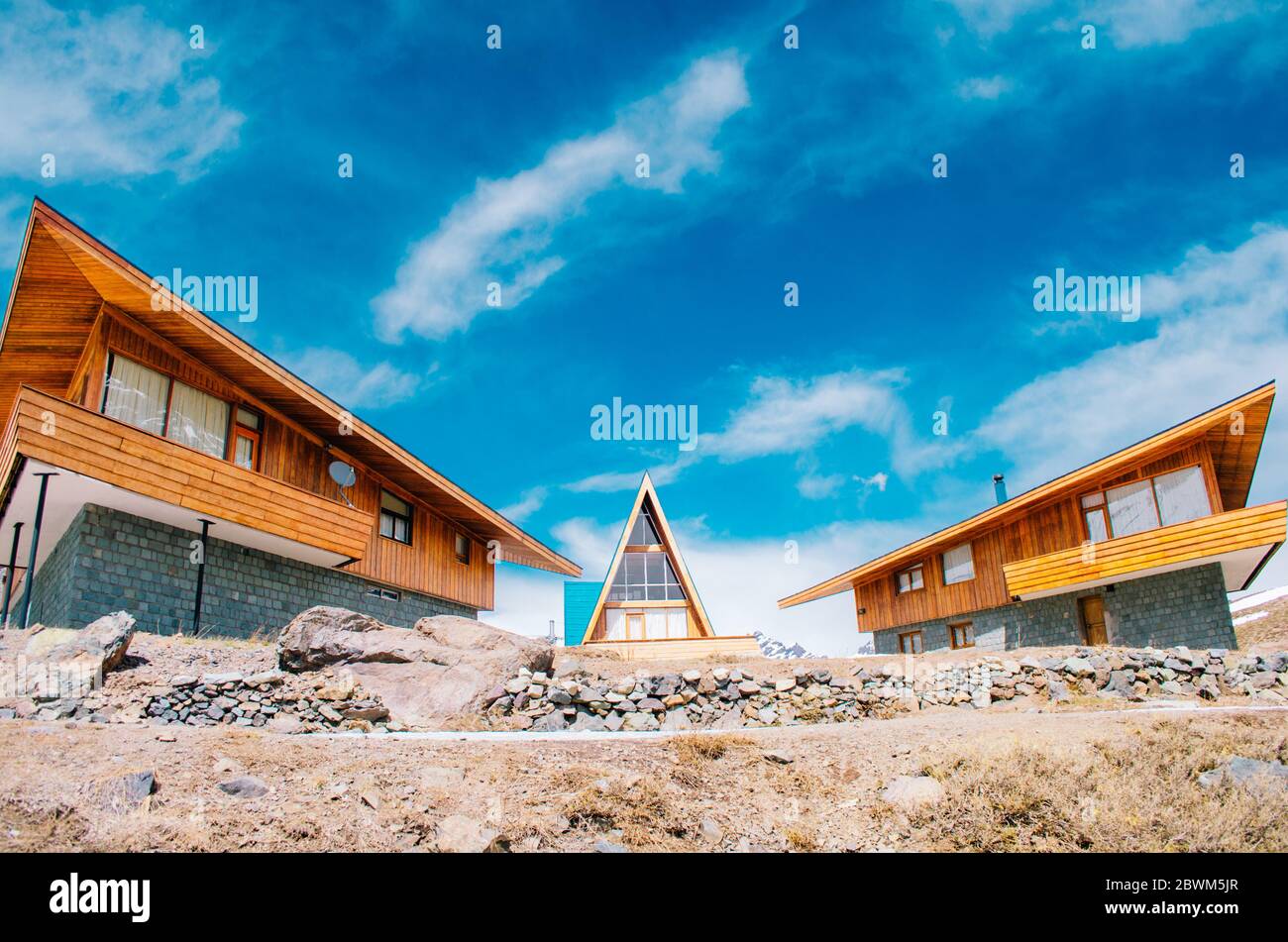 Ein kleiner dreieckiger Bungalow neben zwei anderen Holzhütten in der Nebensaison in den Anden. Stockfoto