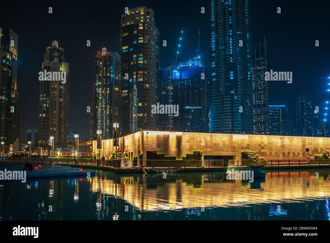 Pool mit Spiegelung und beleuchteten hohen Gebäuden in der Nacht in Dubai, VAE. Stockfoto