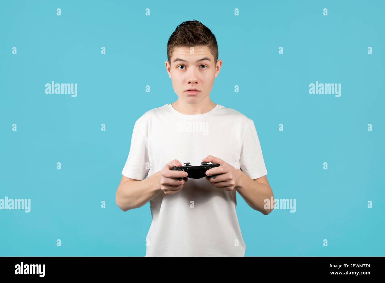 Netter Teenager mit einem modifizierten Joystick in Händen auf einem blauen Hintergrund Stockfoto