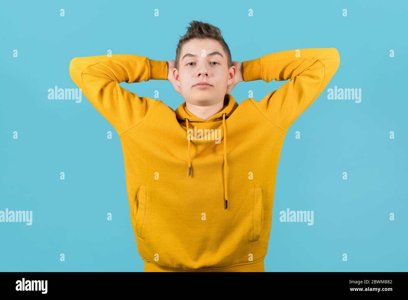 Moderner Teenager in heller Kleidung hält seine Hände hinter dem Kopf und zeigt Selbstvertrauen Stockfoto