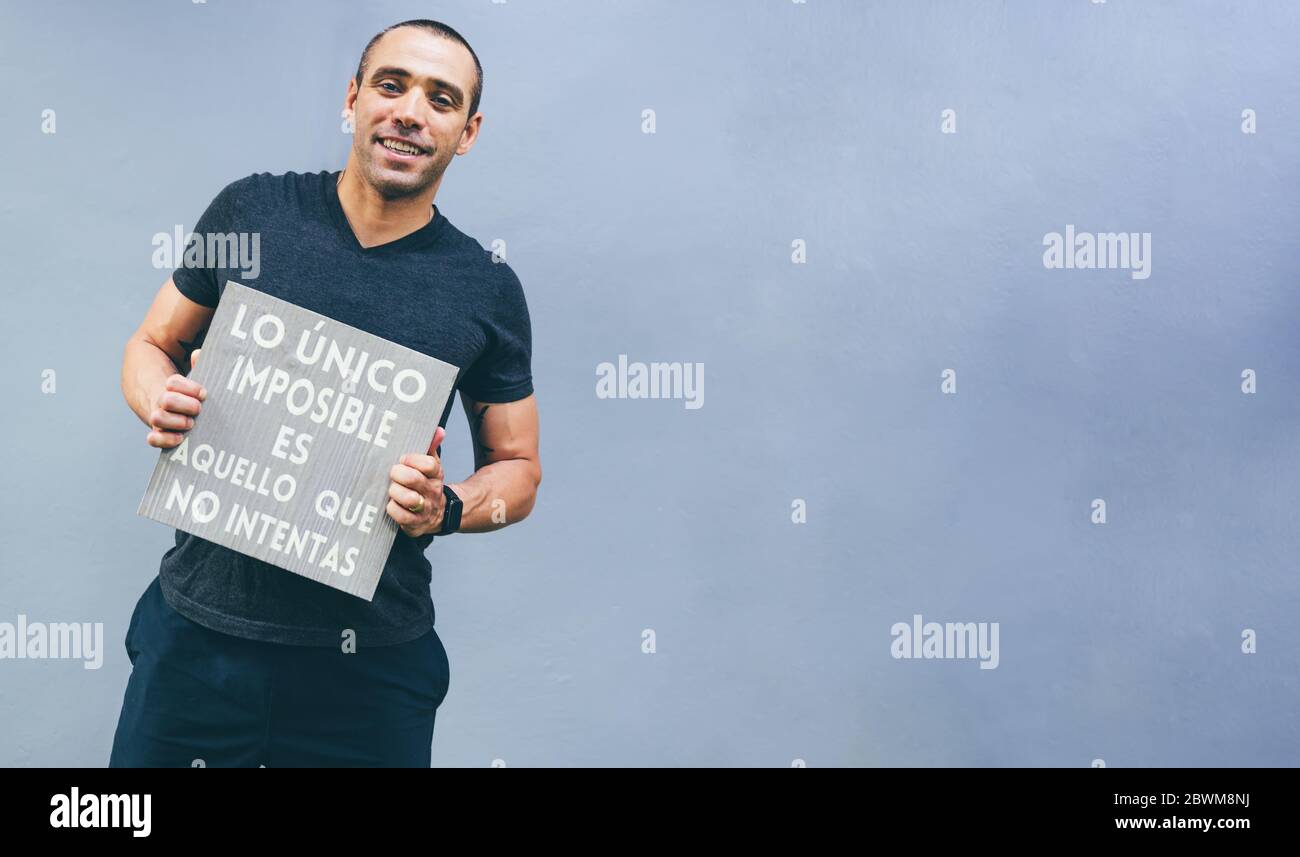 Lateinischer Junge hält Plakat in Händen mit inspirierender Botschaft auf isoliertem Hintergrund. Inspirationskonzept Stockfoto