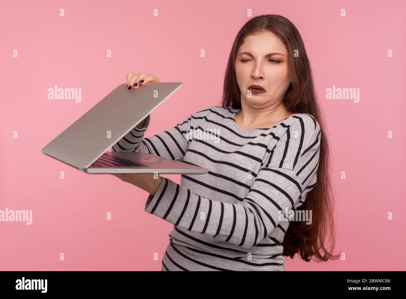 Porträt von Mädchen in gestreiften Sweatshirt Schließung Laptop, mit Misstrauen und Misstrauen auf dem Bildschirm, Angst vor unbekannter Software, Versagen Stockfoto