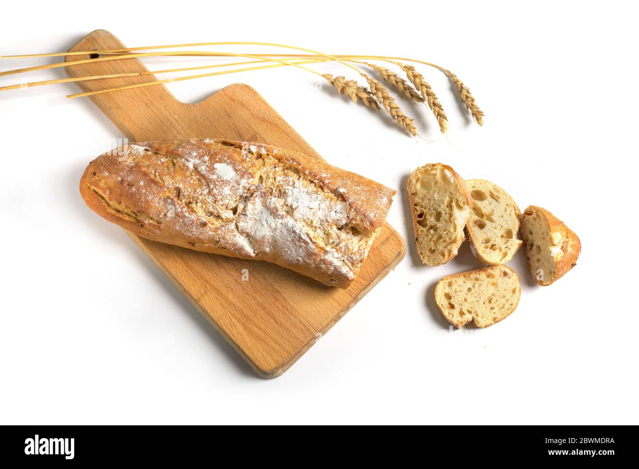 Halb geschnittenes Baguette oder französisches Brot mit Zwiebeln auf einem Küchenbrett und einige Weizenohren mit Schatten auf weißem Hintergrund isoliert gebacken, kopieren Raum, Stockfoto
