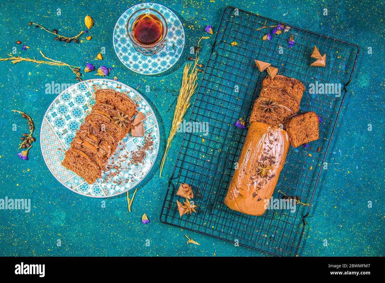 Kakaokuchen mit Schokoladenglasur auf Gitter neben einer Tasse Tee Stockfoto