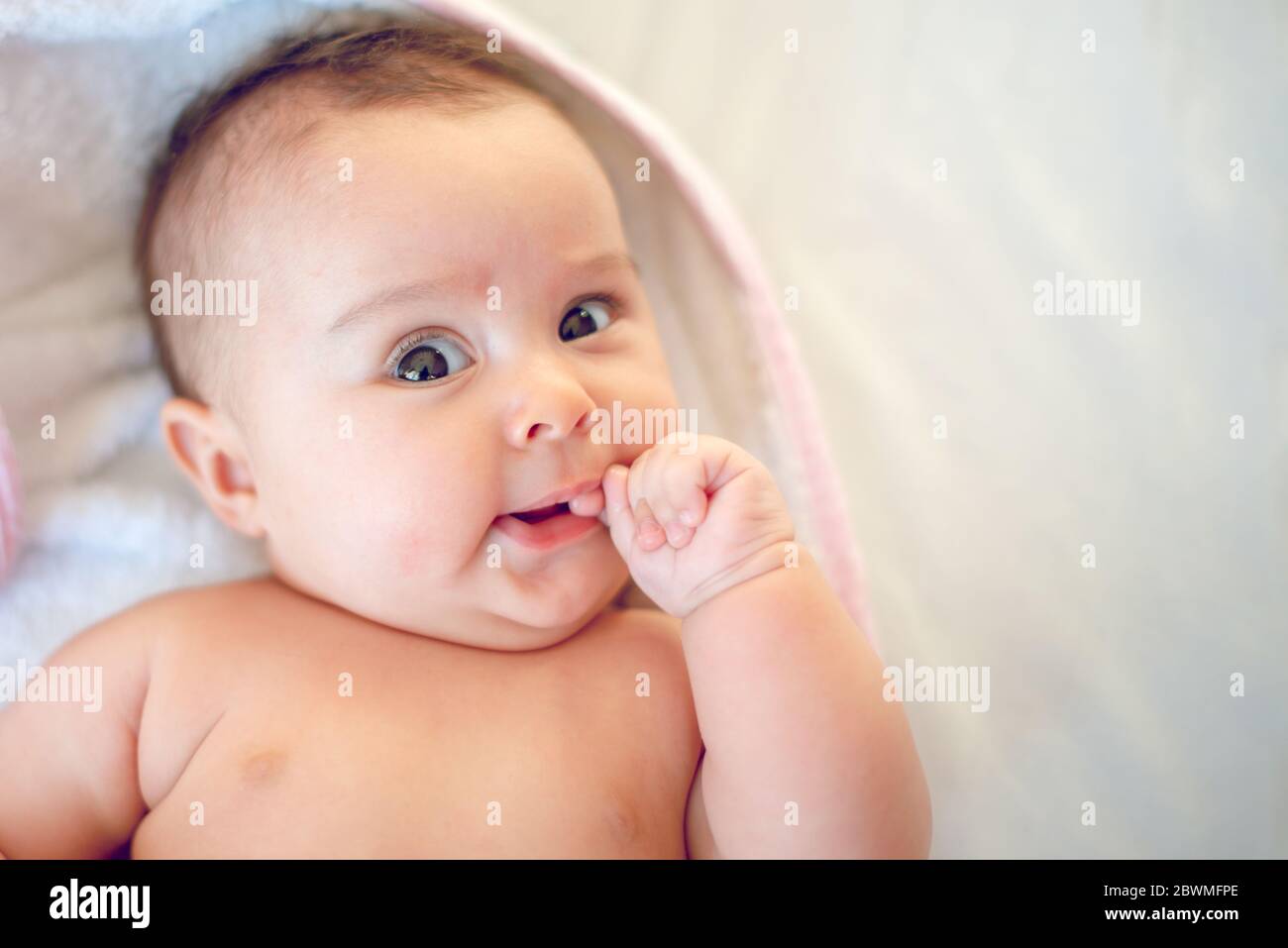 Porträt eines kleinen neugeborenen Mädchens, das ihren Finger im Mund hat Stockfoto