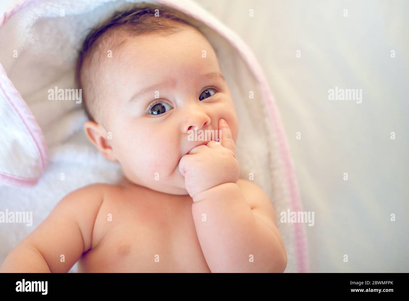 Porträt eines kleinen neugeborenen Mädchens, das ihren Finger im Mund hat Stockfoto