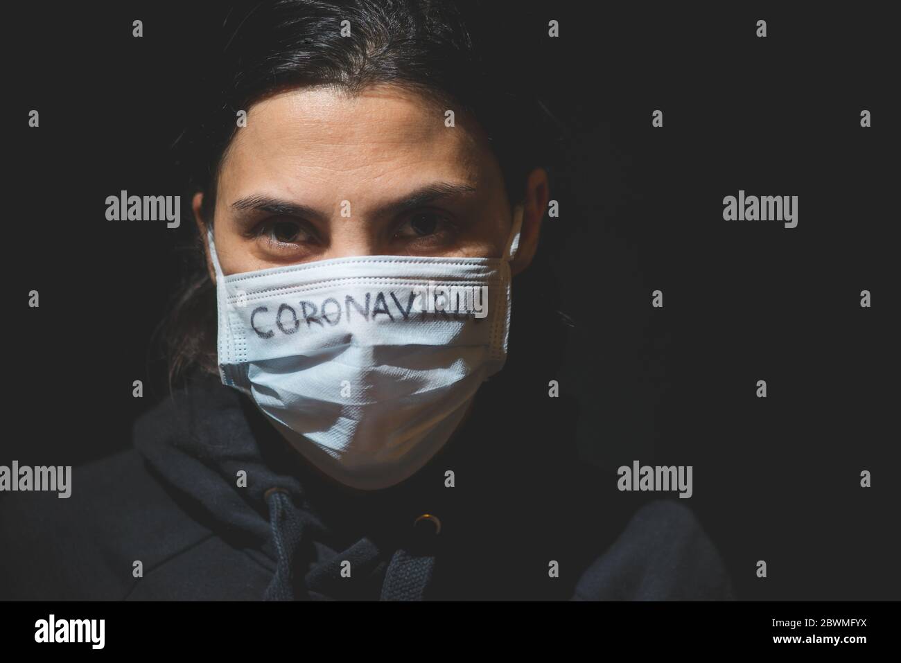 Eine Frau, die sich im Dunkeln versteckt, fürchtet Coronavirus, einen unsichtbaren Mörder. Stockfoto