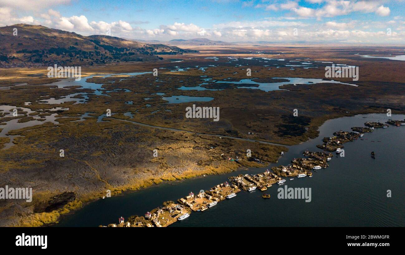 Eine Luftaufnahme von Uros schwimmenden Inseln Siedlungen am Titicaca-See, Peru mit Hügeln, Plantage von Totora, und Blick auf die Küste in Puno. Stockfoto