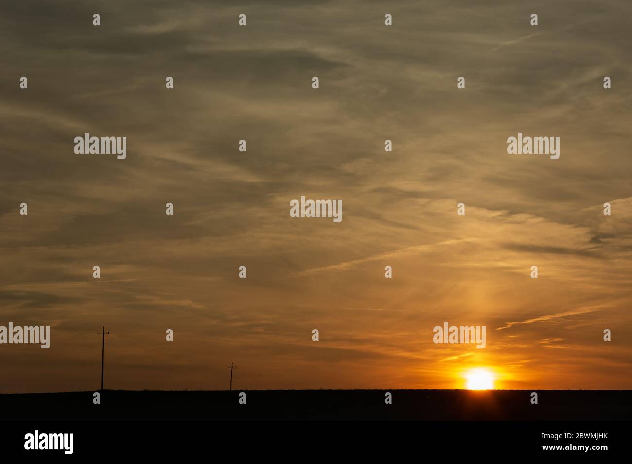 Sonnenuntergang über dem Horizont, abstrakte Wolken und elektrische Pole Stockfoto