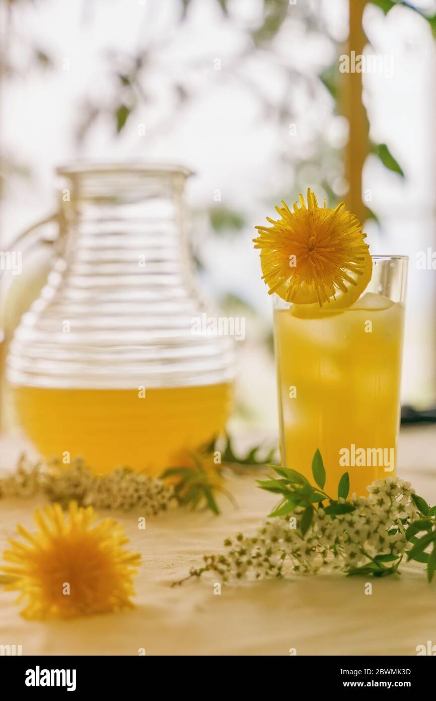 Zitruslimonade in einem Glas und einem Krug steht auf einem Tisch inmitten frischer Blumen Stockfoto