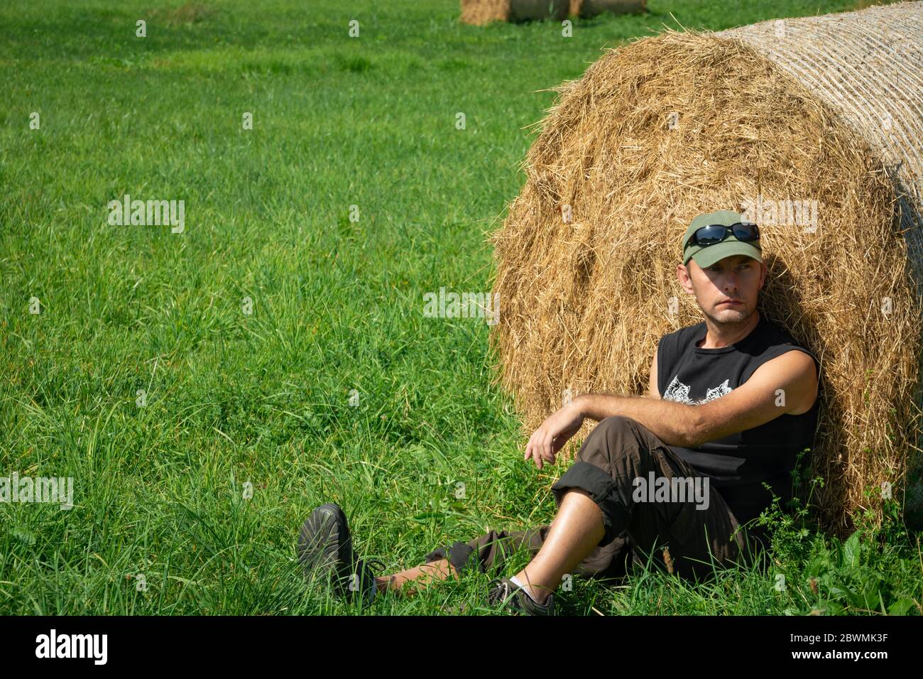 Müde Mann auf dem Gras und Heuballen sitzen, Sommer Blick Stockfoto