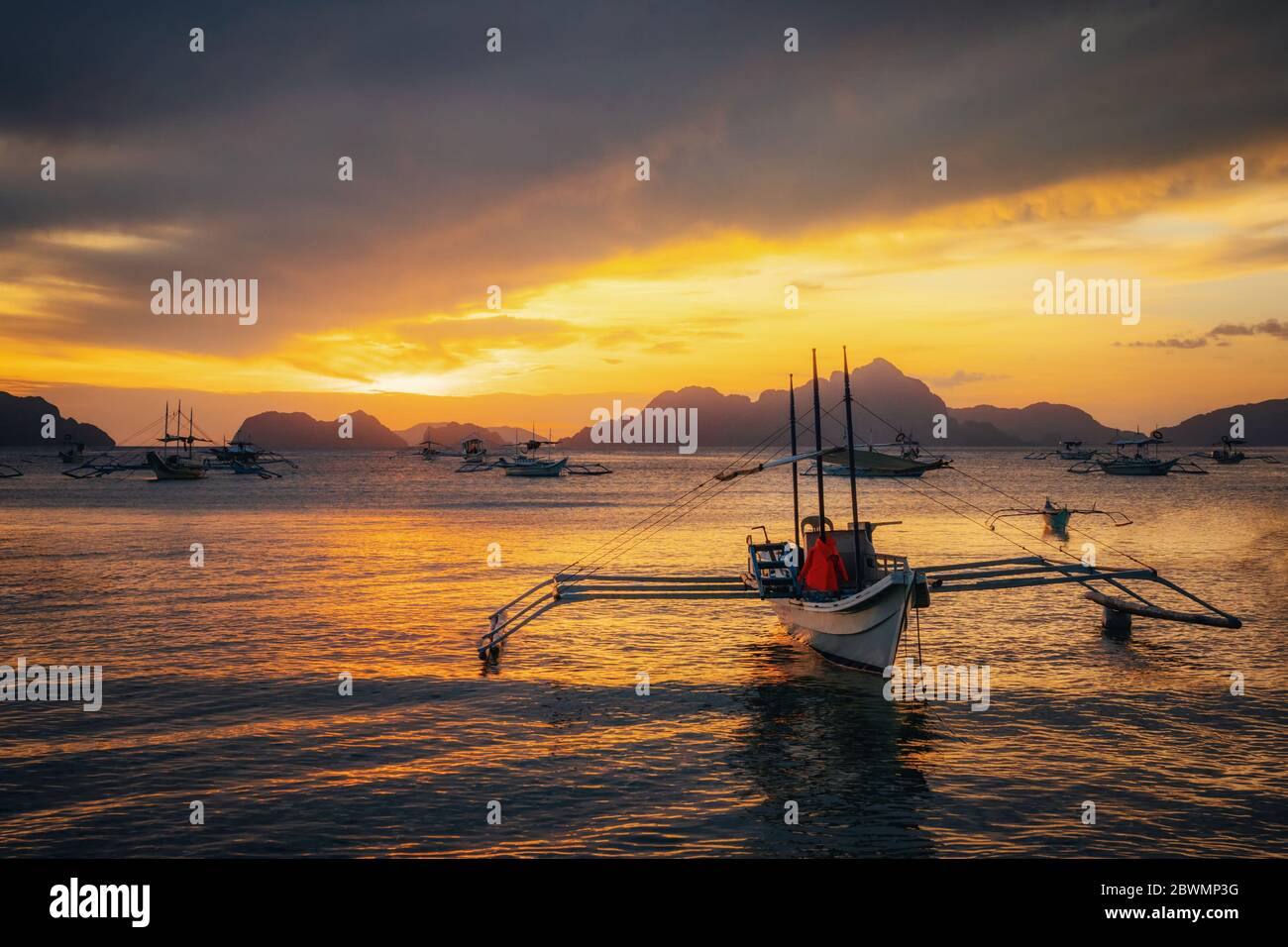 Traditionelle philippinische Boote in Corong-Corong Strand in El Nido bei Sonnenuntergang leuchten. Palawan, Philippinen Stockfoto