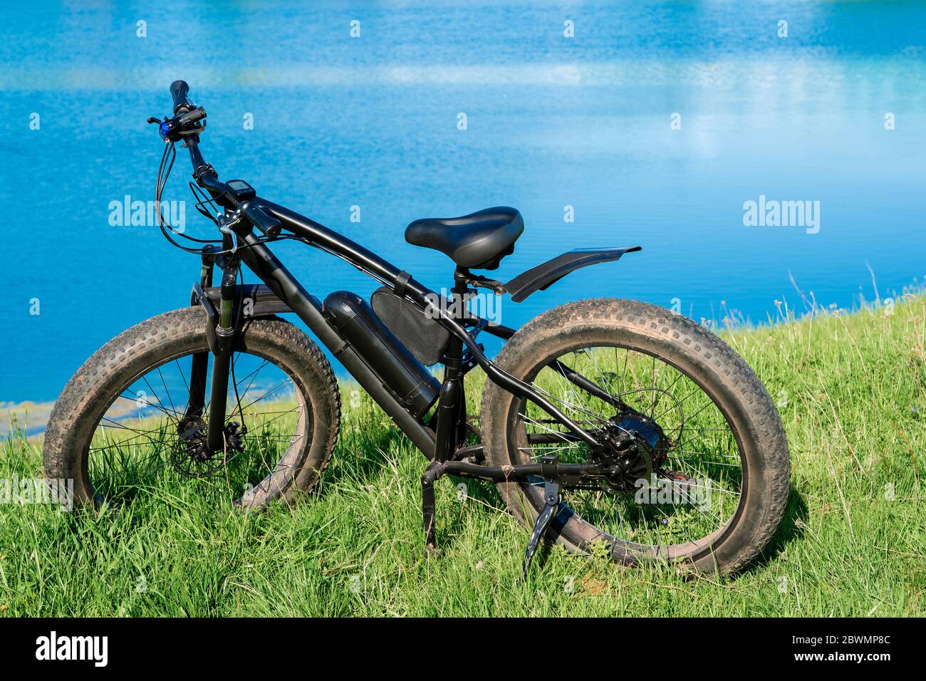 Schwarzes E-Bike mit dicken Rädern auf dem Gras in der Nähe des Sees.  Fatbike Stockfotografie - Alamy